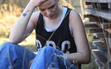 Junge Frau (Cynthia) sitzt allein im Garten