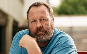 Ein bärtiger Mann blickt  traurig in die Kamera.
